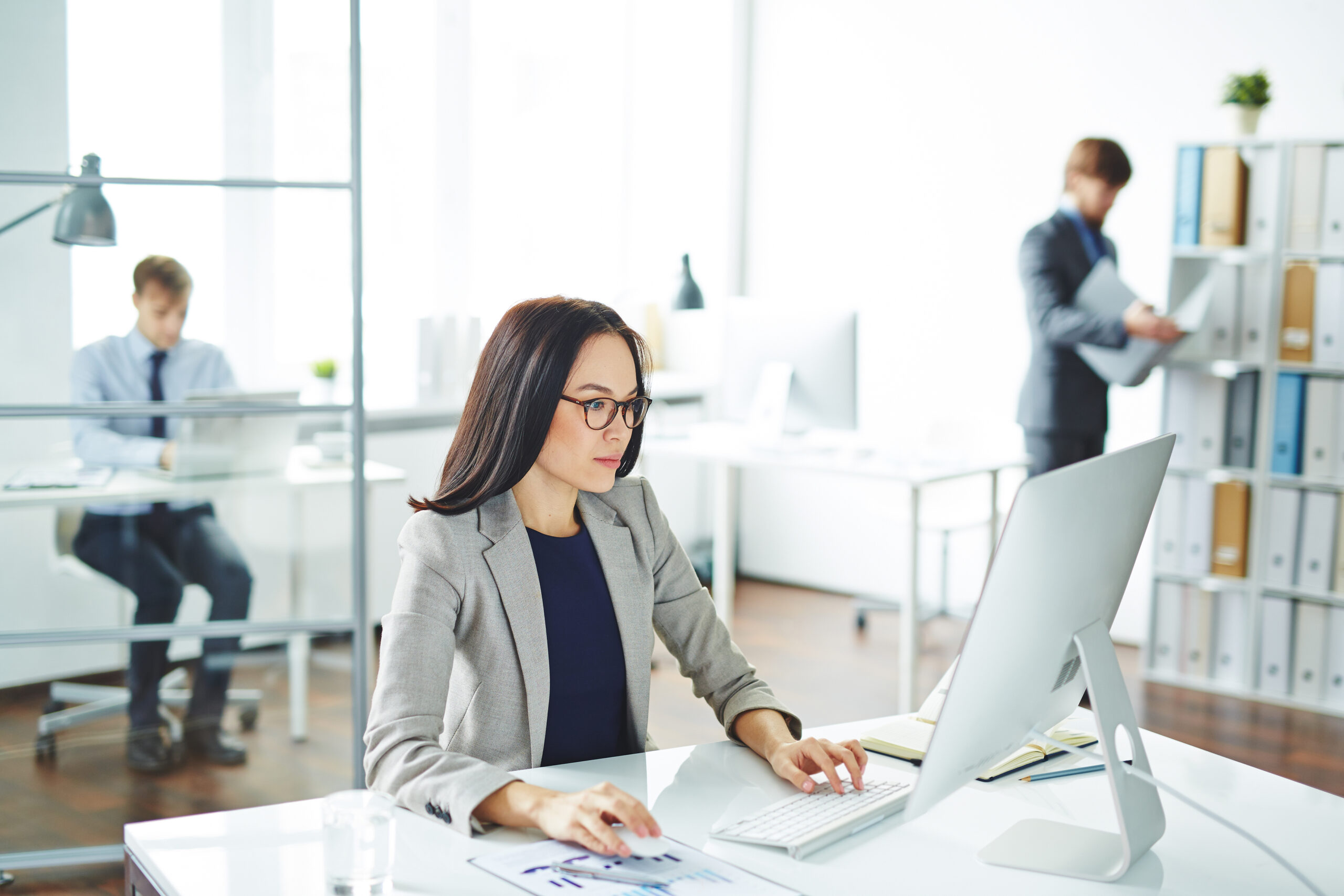 Femme d'affaires travaillant sur son ordinateur dans un bureau partagé, type open-space.