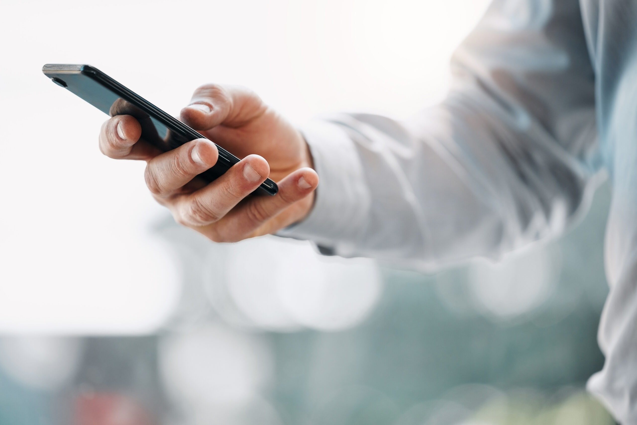 Zoom sur la main d'un homme d'affaire tenant son smartphone, qui à bénéficié d'une préparation de son terminal